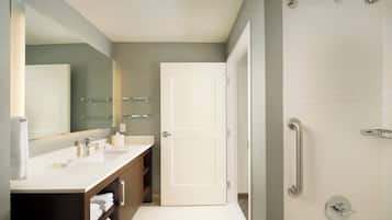 A modern bathroom with a double sink, a large mirror, a glass shower enclosure, and a white door.