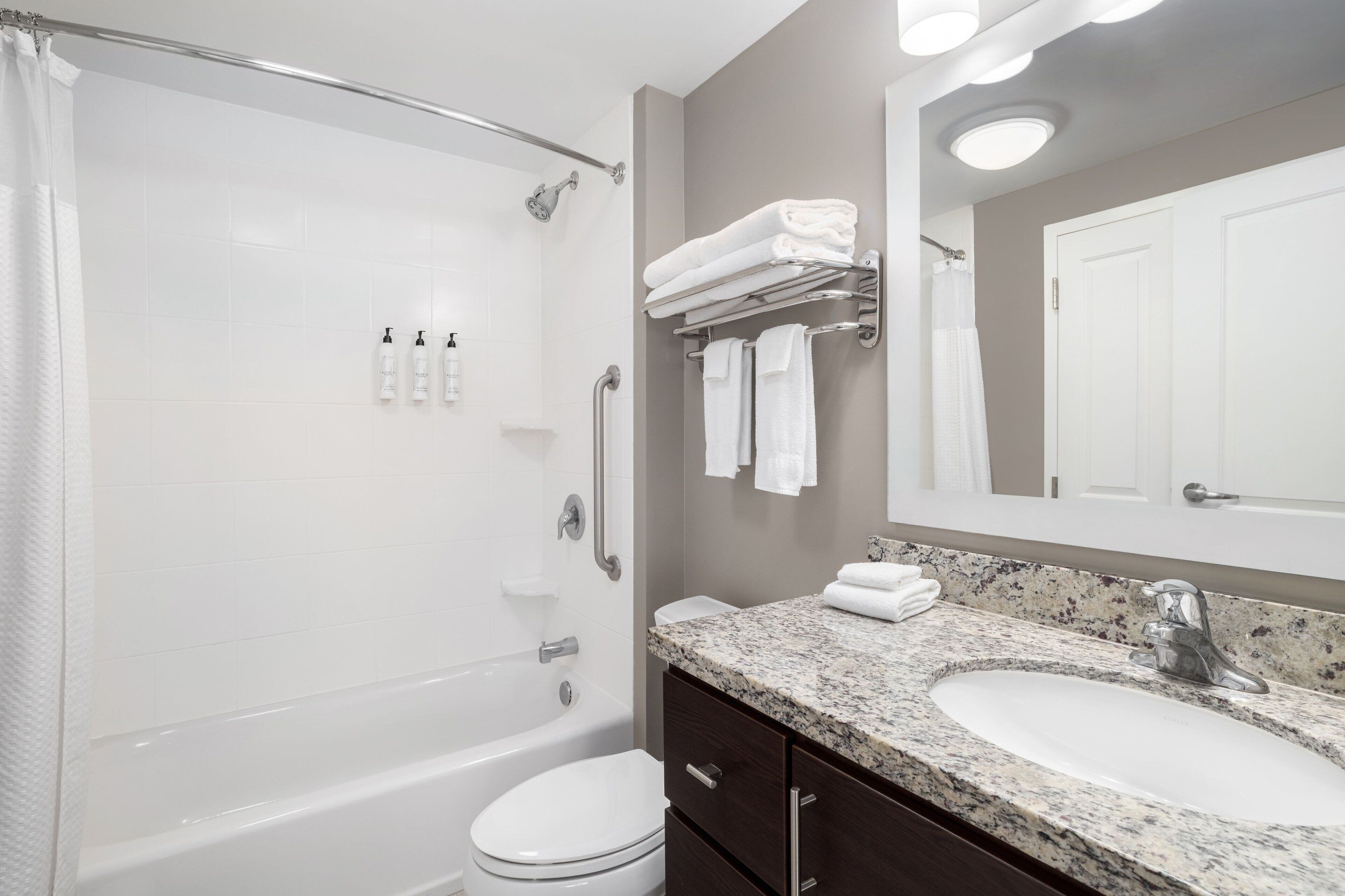 Un baño moderno con ducha, inodoro, lavabo y un espejo grande.