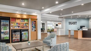 Vestíbulo de hotel con recepción, zona de estar y máquinas expendedoras.