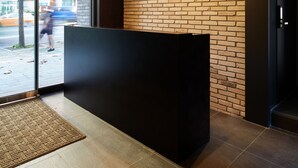 A reception area with a brick wall, a black reception desk, and a large glass door leading outside.