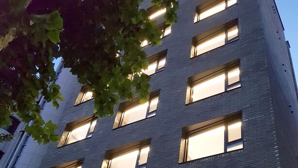 A multi-story building with illuminated windows and a sign that reads "CLEO".
