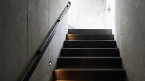 A concrete staircase with a handrail, leading to a bright area at the top.