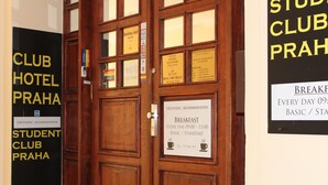 Una puerta de madera con varios letreros, incluyendo uno de un club estudiantil, uno que anuncia desayuno y otro de un club de spa.