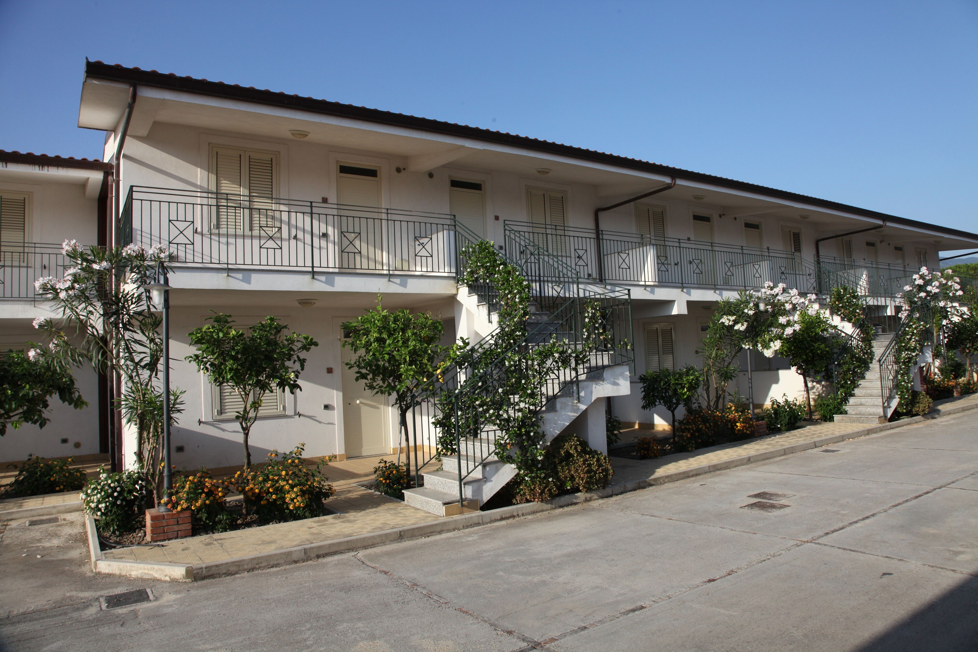 A two-story building with balconies, a staircase, and a sidewalk.