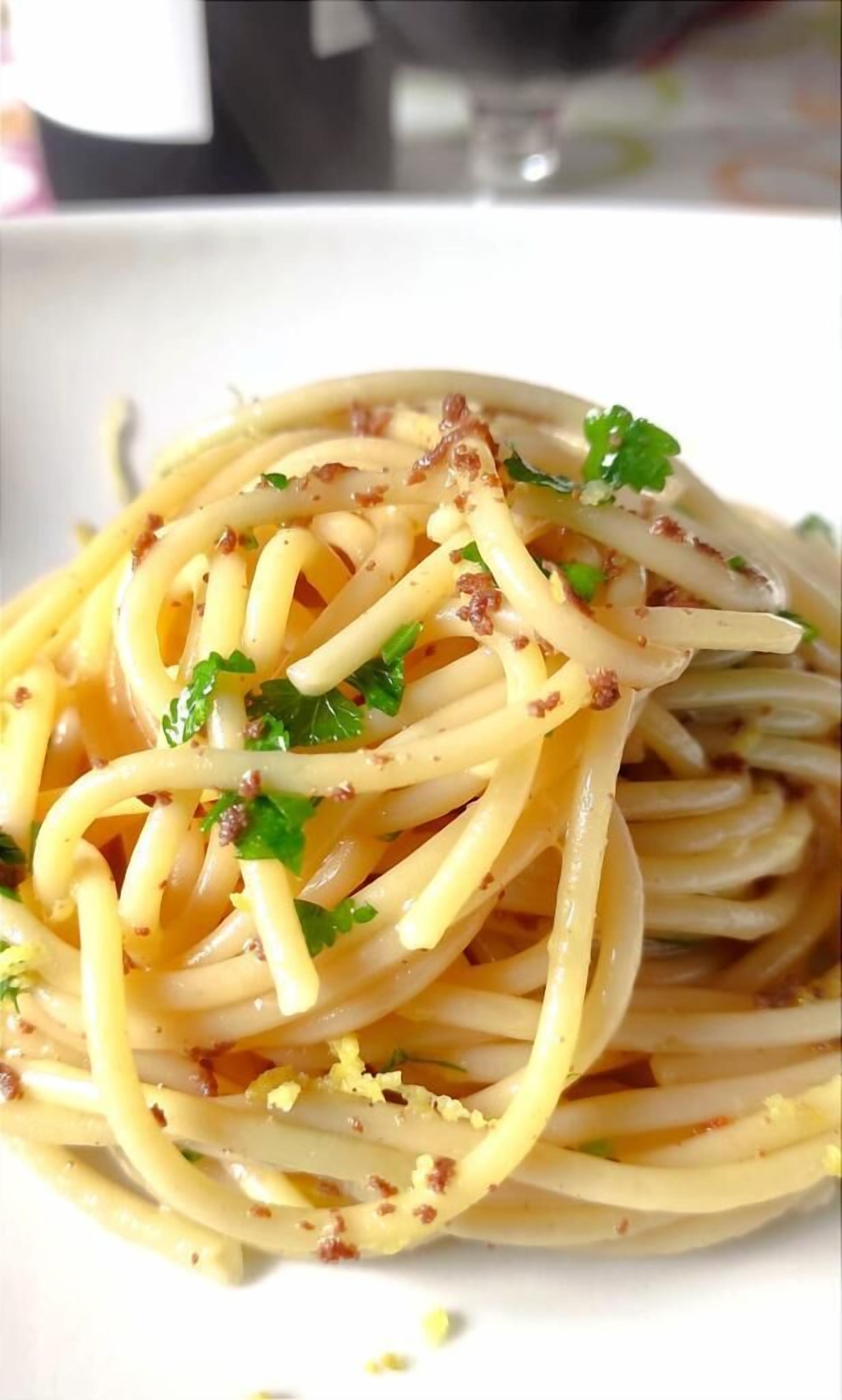 A plate of spaghetti with a creamy sauce, garnished with herbs and bits of bacon.