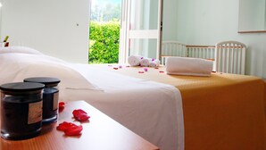 Una habitación de hotel con una cama, una mesa de madera con velas y vistas a zonas verdes por la ventana.