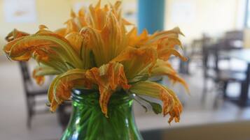 Eine grüne Vase mit welken, orangefarbenen Blüten.