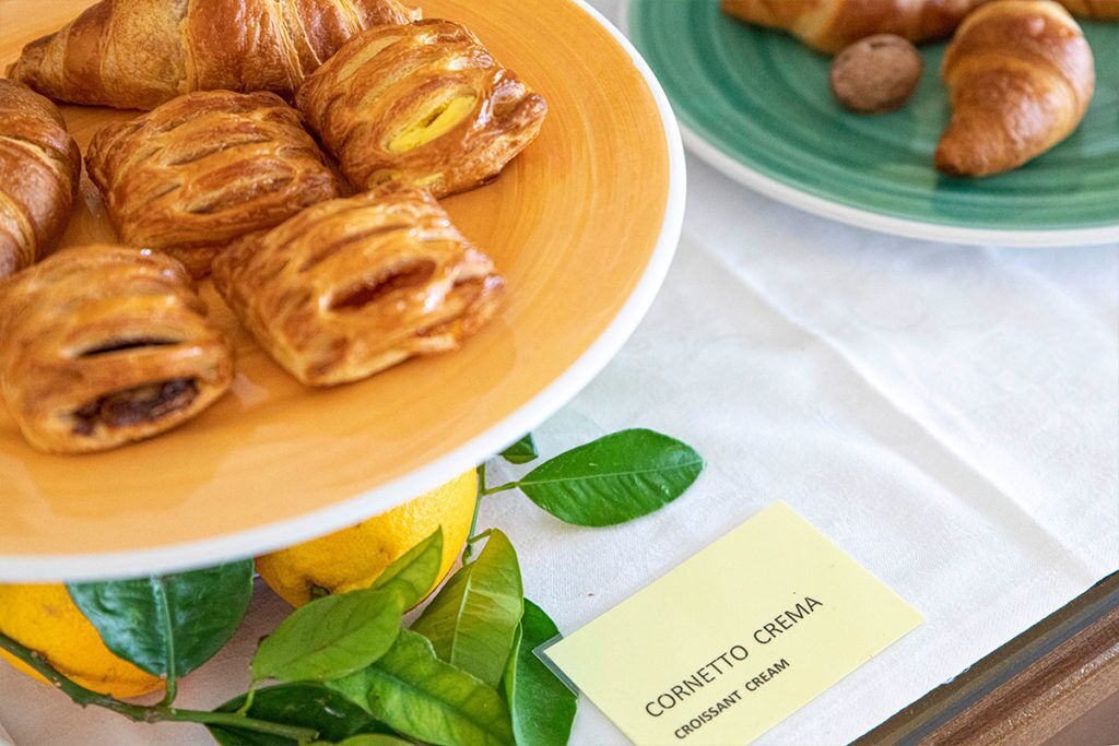 Un plato de croissants y un cartel que indica 'CORNETTO CREMA'.