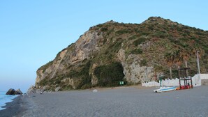 Una playa con un risco rocoso, un bote pequeño y una torre de salvavidas.