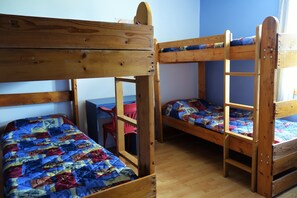 Ein Zimmer mit zwei Etagenbetten, einem Holztisch und einem roten Stuhl.