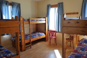 Ein Zimmer mit Etagenbetten, einem Holztisch und einem Stuhl.