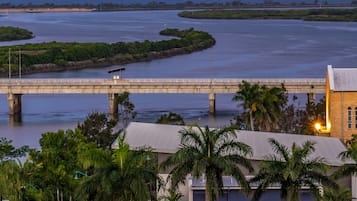 Spanning the river, a simple bridge connects to a building nestled among lush greenery.