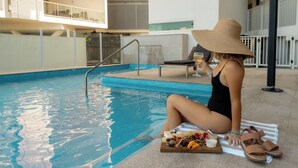 A poolside area with a lounge chair and a buffet table with snacks.