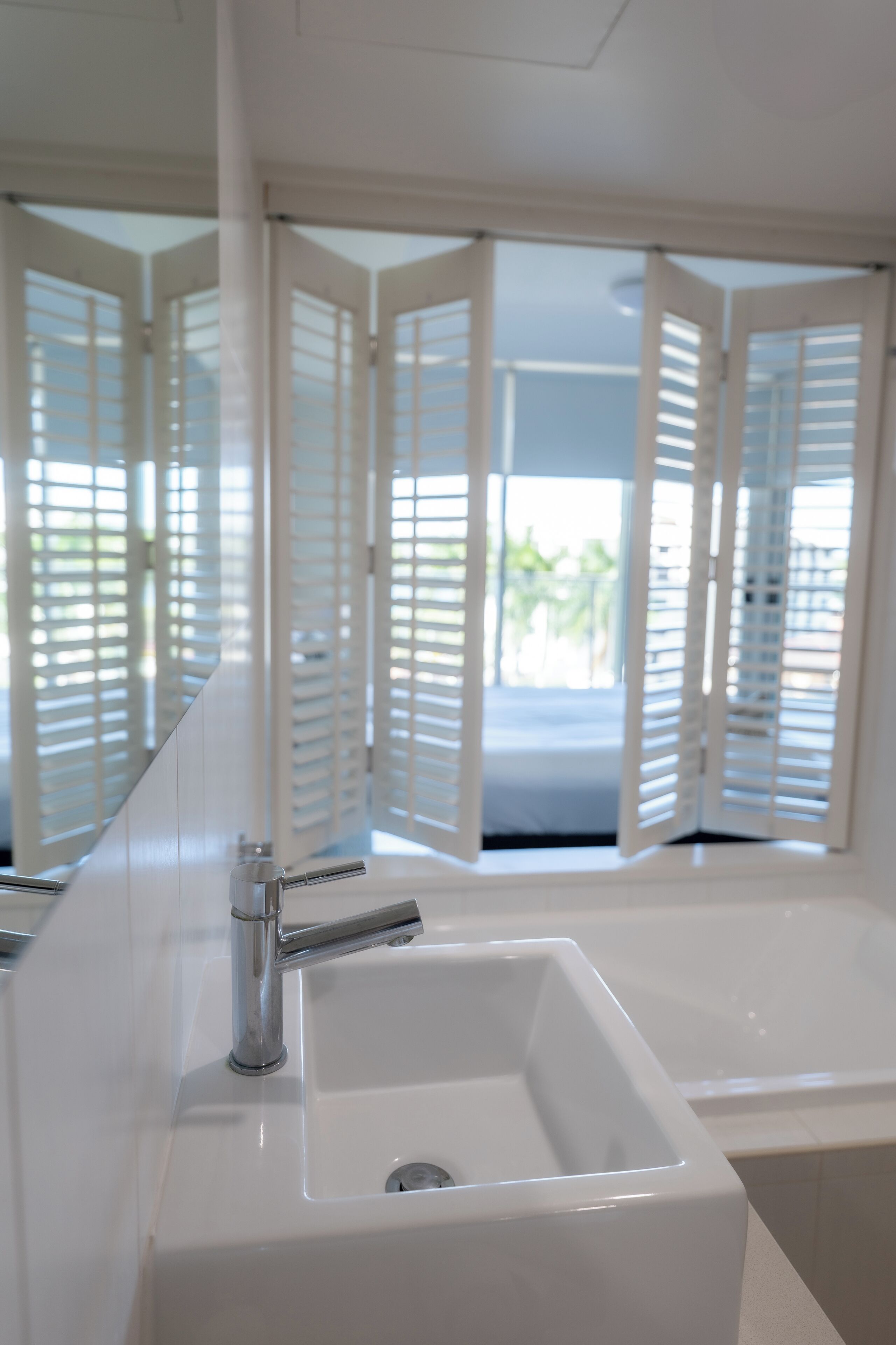 A bathroom with a white sink, chrome faucet, and a large mirror.