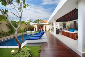 A modern outdoor pool area with lounge chairs and a wooden deck.