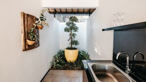 A kitchen with a sink, a potted plant, and a wooden door. - Indi Villas - The Ambika (Seminyak)