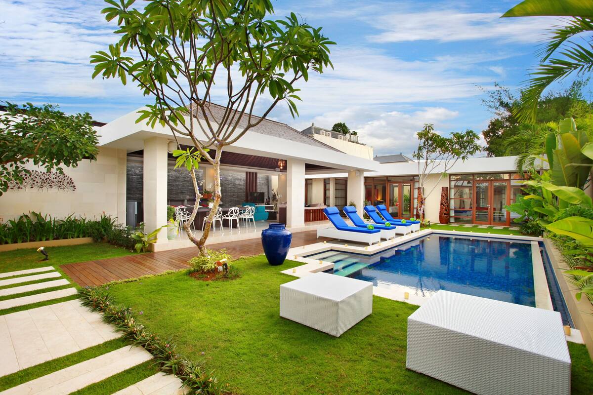 A modern house with a swimming pool, outdoor seating, and a well-maintained garden.