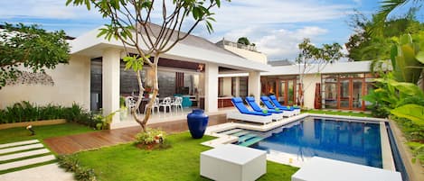 A modern house with a swimming pool, outdoor seating, and a well-maintained garden.