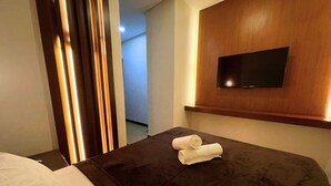 Habitación de hotel con cama, televisor montado en la pared y un par de toallas sobre la cama.