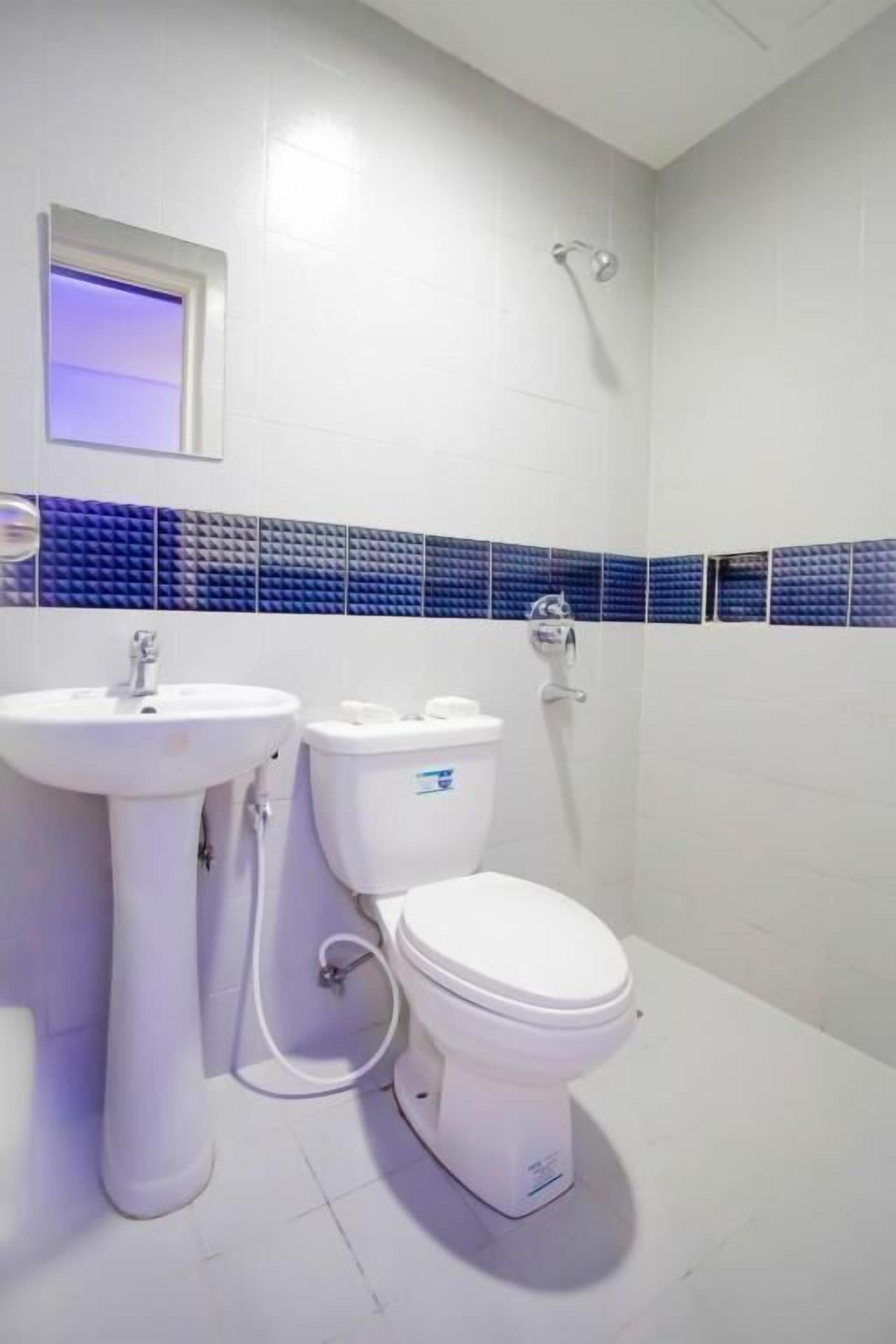 Un baño con lavamanos, inodoro y ducha blancos.