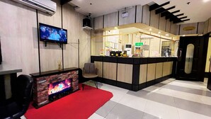 Un vestíbulo de hotel con televisor, chimenea, mostrador de recepción y área de registro.