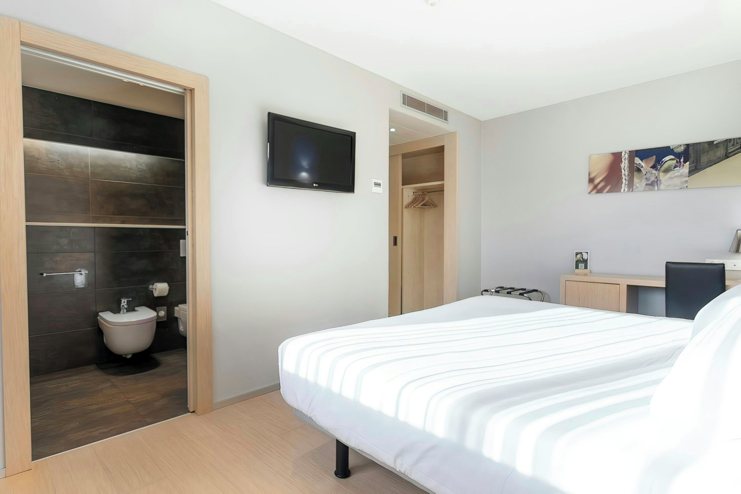 Une chambre d’hôtel équipée d’un lit, d’une télévision, d’une armoire et d’un bureau.