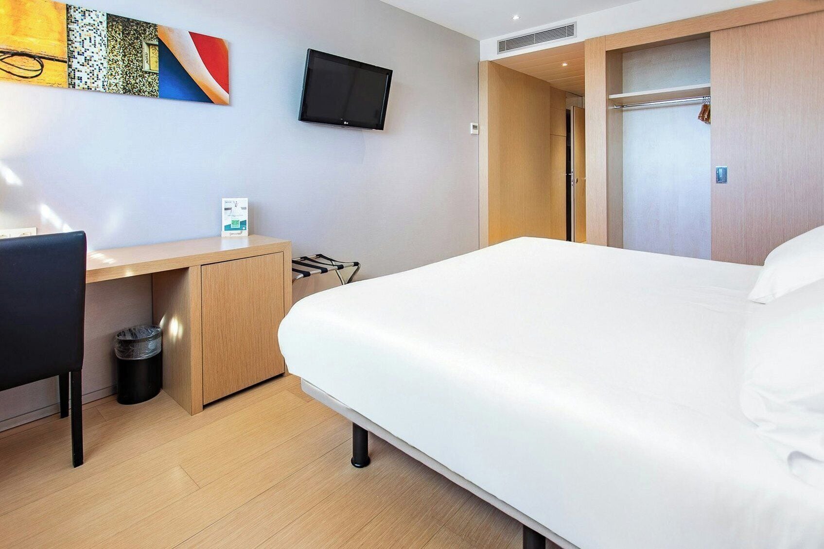 Une chambre d’hôtel équipée d’un lit, d’un bureau, d’une chaise, d’une télévision et d’une armoire.