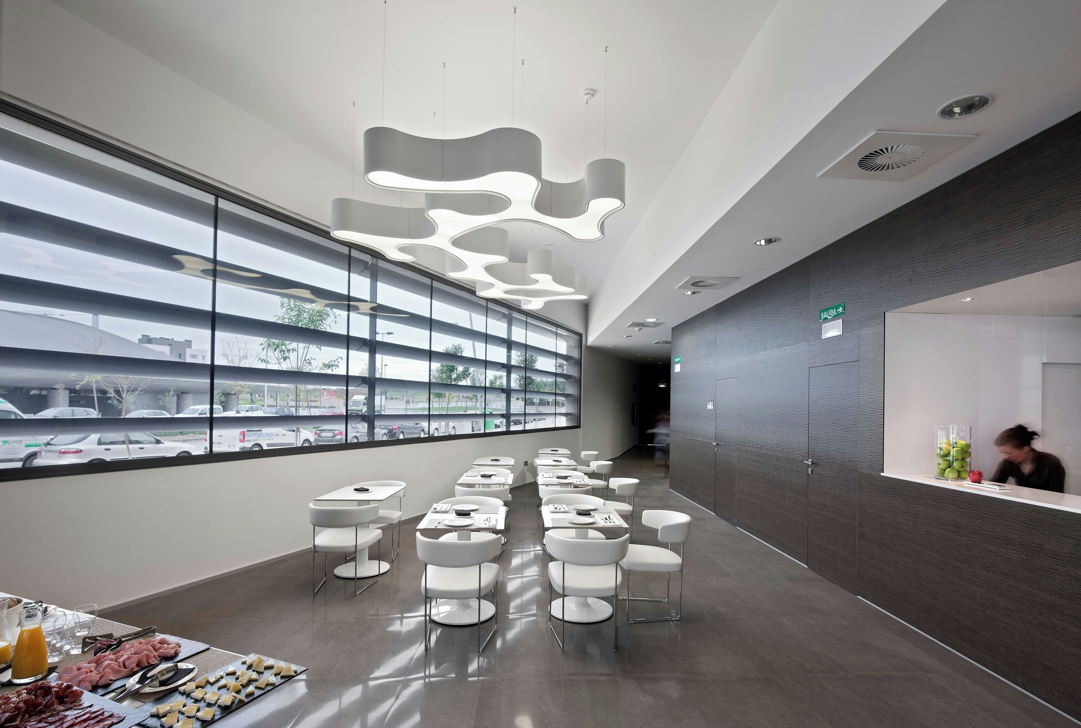 A modern hotel lobby with a reception desk, seating area, and large windows offering a view of the street.