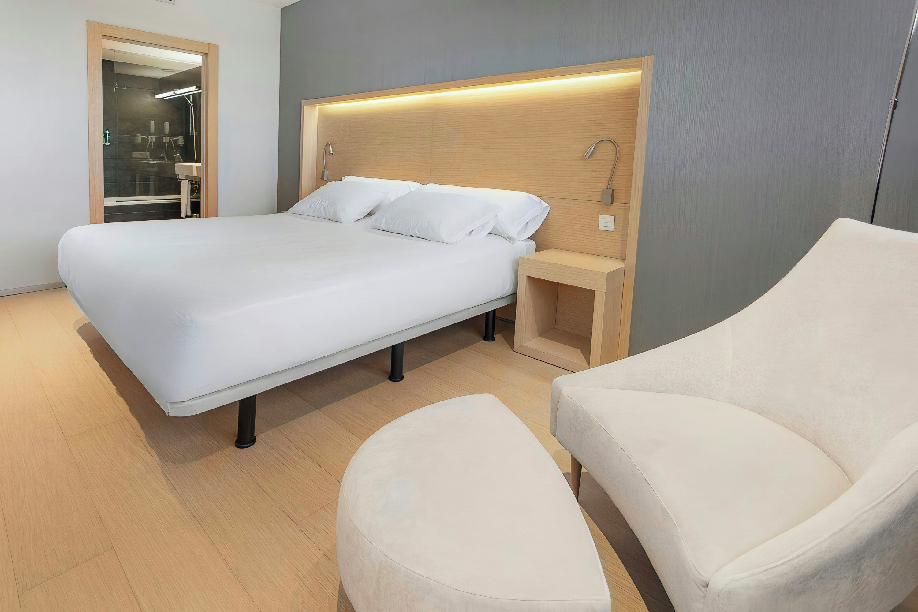 A modern hotel room with a large bed, bedside tables, and a seating area.