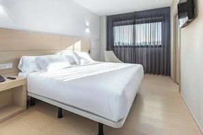 A modern hotel room with a large bed, a bedside table with a phone, and a TV mounted on the wall. - Sercotel Hola Tafalla (Tafalla)