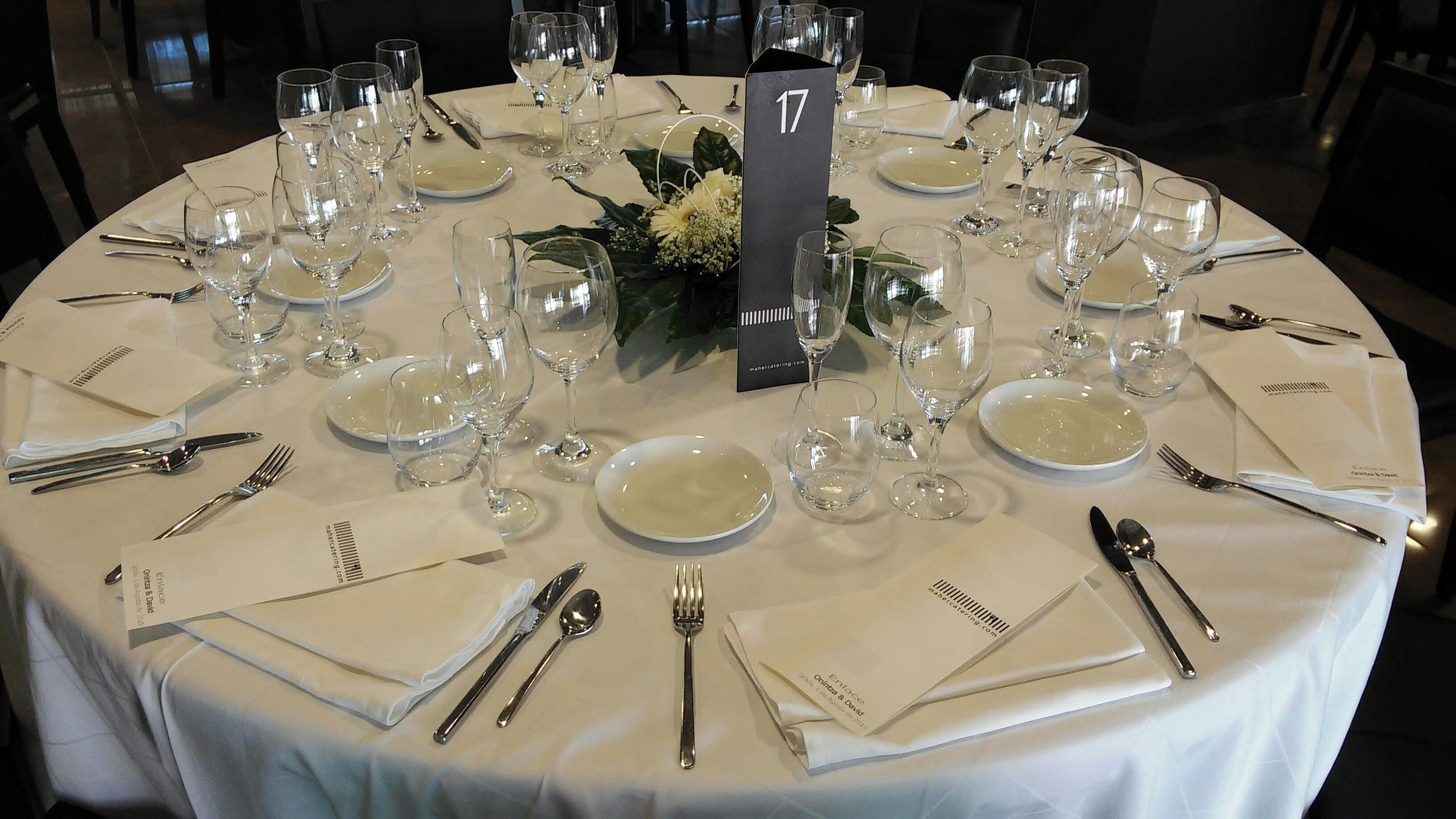 A round table set for a formal dining event with numbered place cards, clear glassware, and neatly folded napkins.
