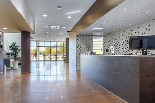 Un área de recepción moderna con mostrador, televisor montado y pared con diseño.