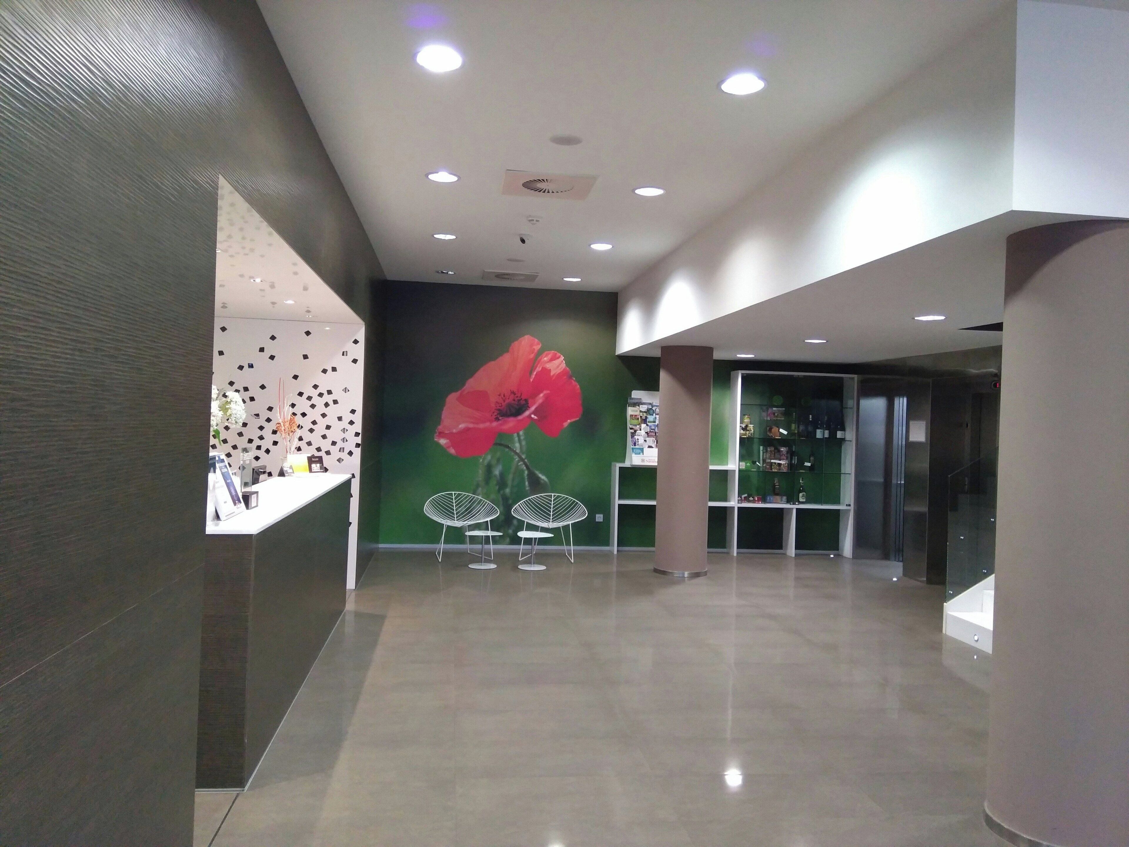 Un vestíbulo moderno con un mural de amapolas, una recepción y un ascensor de vidrio.