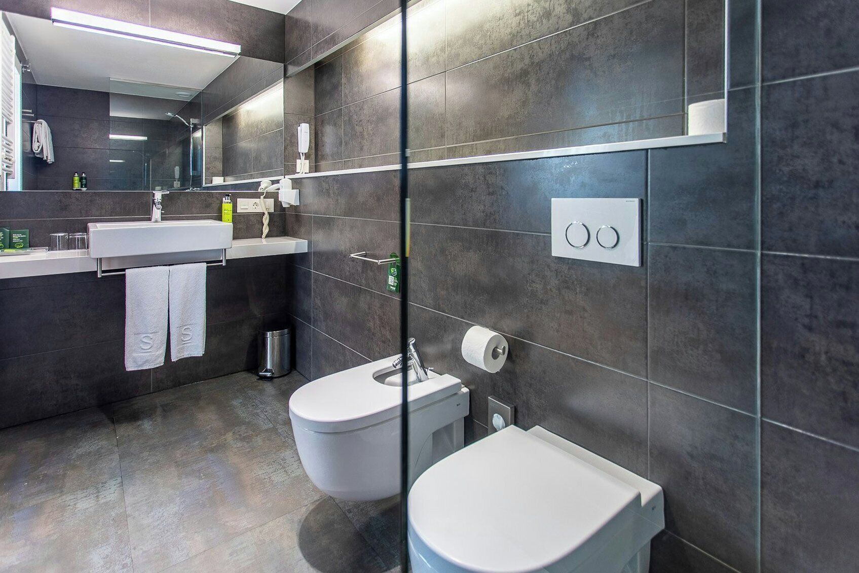 A modern bathroom with a toilet, bidet, and sink.
