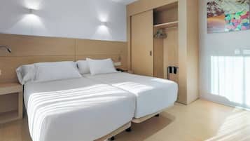 Una habitación de hotel moderna con una cama grande, armario empotrado y un cuadro en la pared.
