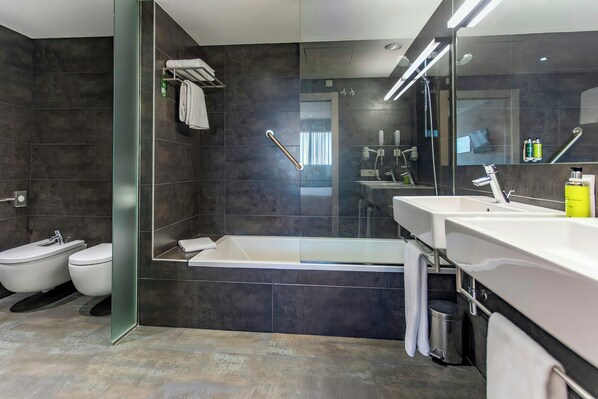 A modern bathroom with a glass shower enclosure, a bathtub, two toilets, a large mirror, and a vanity with a sink. - Sercotel Hola Tafalla (Tafalla)