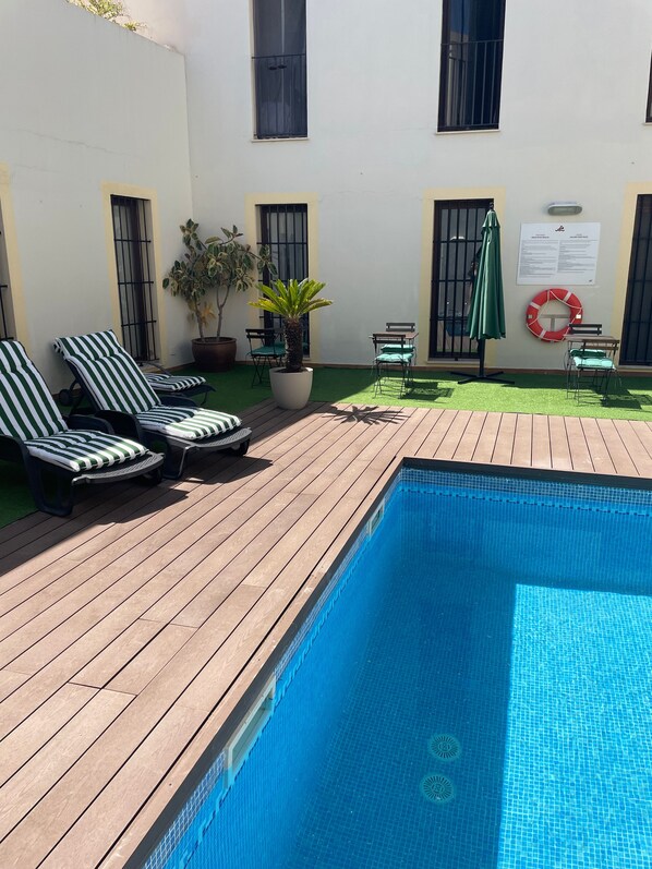 A swimming pool with lounge chairs and a potted plant. - Palacio de Luja (El Puerto de Santa Maria)