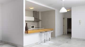 Una cocina moderna con armarios blancos, encimera de madera y dos taburetes blancos.