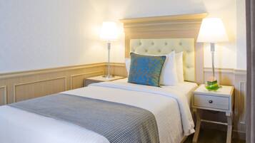 A neatly made bed with a tufted headboard, two bedside lamps, and a small drawer.