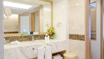 A modern bathroom with a large mirror, marble countertop, and a small vase with flowers.