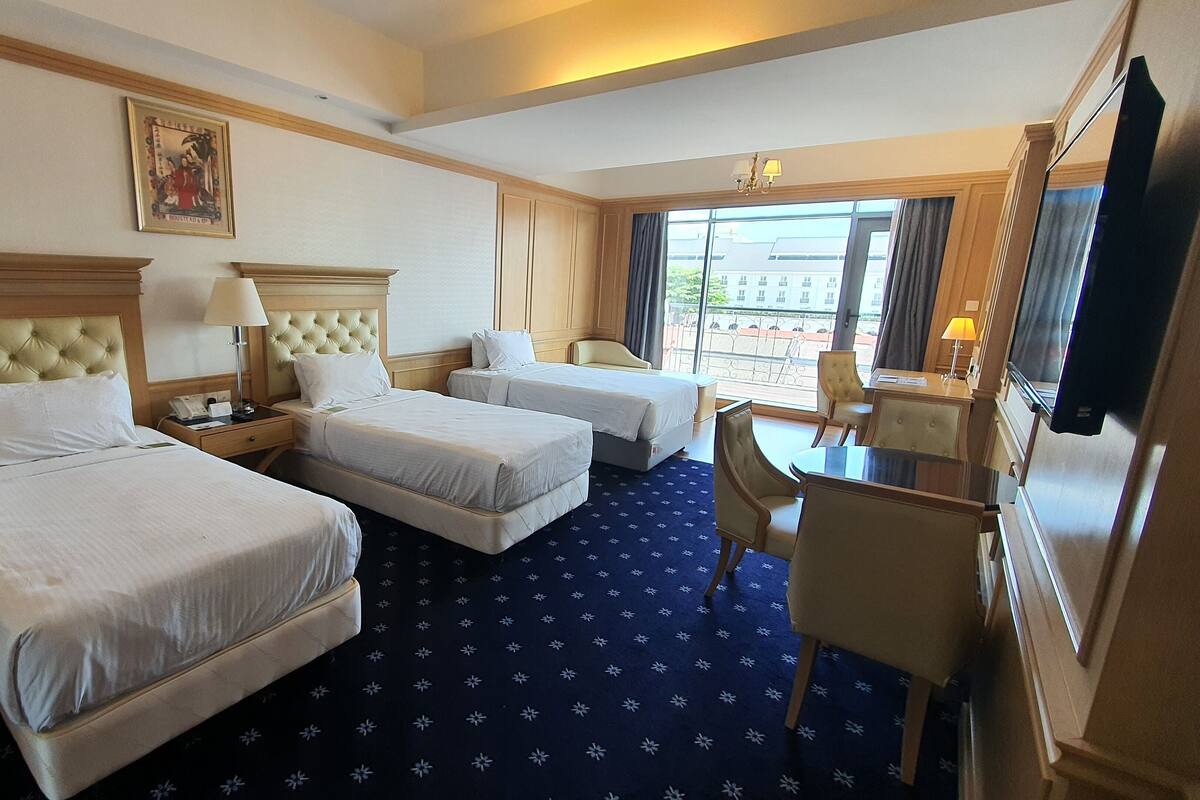 Ein Hotelzimmer mit zwei Betten, einem Schreibtisch, einem Sessel, einem Fernseher und einem Fenster mit Blick.