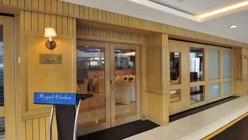 A hotel lobby with wooden paneling, a reception desk, and a sign reading "Royale Chulan Penang."
