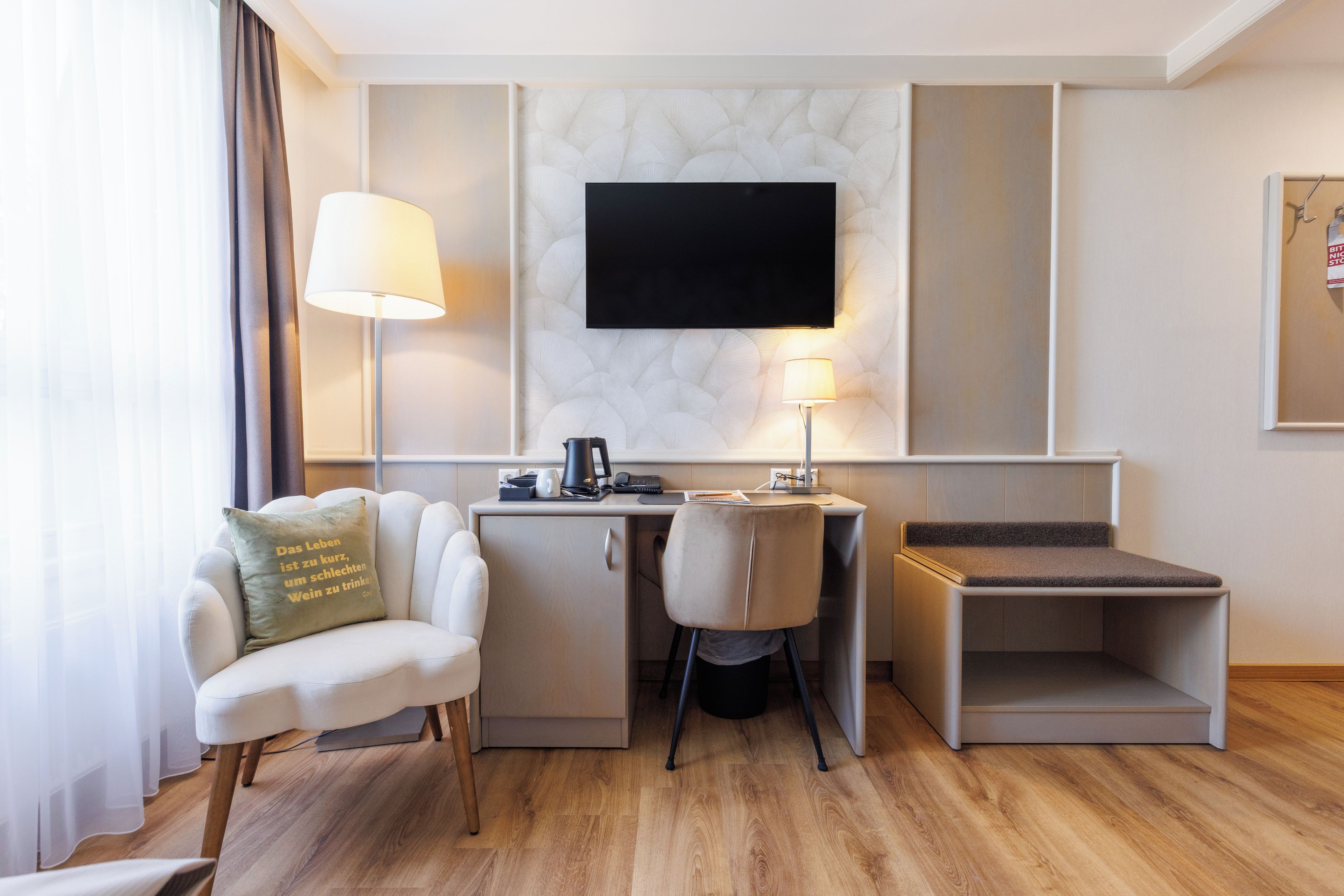 Ein modernes Hotelzimmer mit Schreibtisch, Stuhl und einem flachbildfernseher an der Wand.