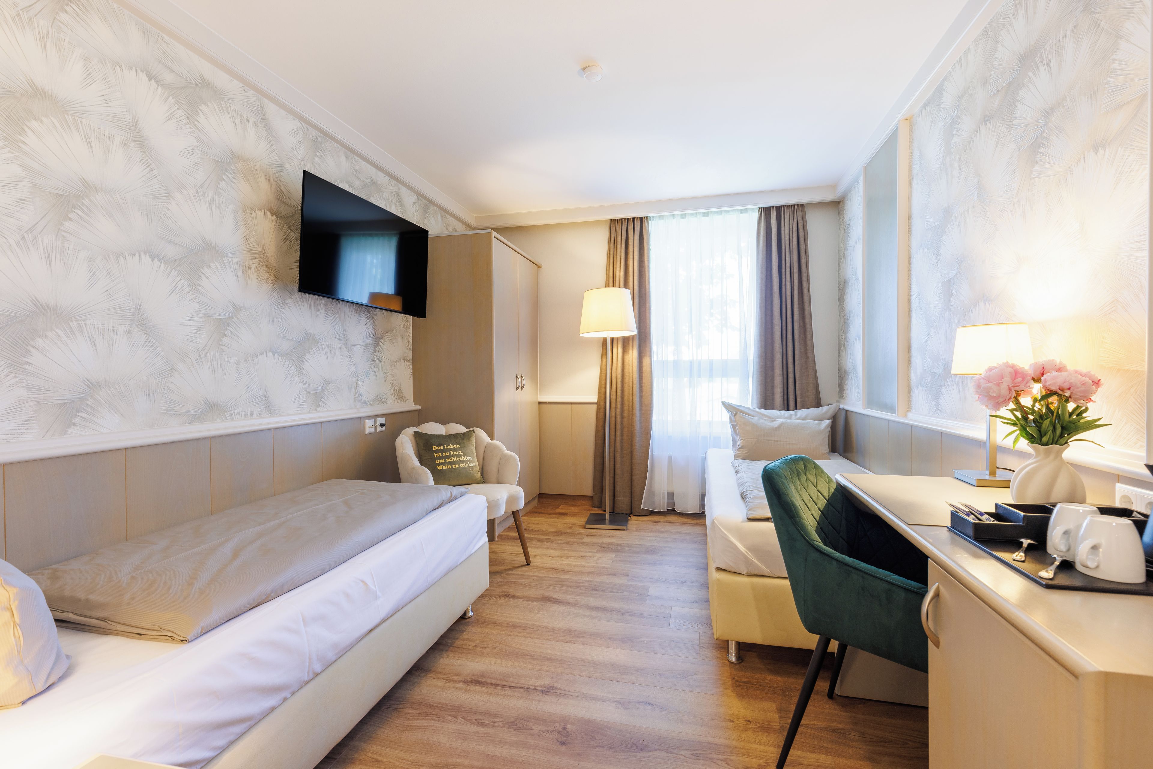 Una habitación de hotel con una cama, un escritorio, una silla, un televisor y una ventana con cortinas.