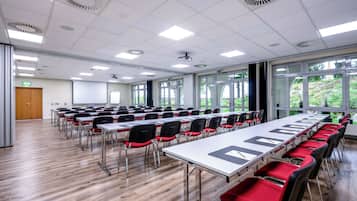 Une salle de conférence équipée de longues tables, de chaises et d’un écran de projection.