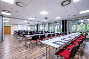 A conference room with long tables, chairs, and a projector screen. - Weinberghotel Edelacker (Freyburg)