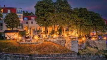 Un cortile con posti a sedere all'aperto, pareti in pietra e alberi.
