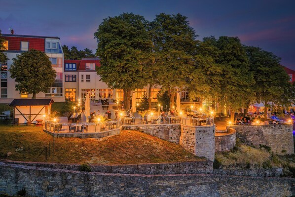 A courtyard with outdoor seating, stone walls, and trees.