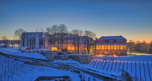 A snow-covered landscape with a building featuring large windows and a red roof. - Weinberghotel Edelacker (Freyburg)