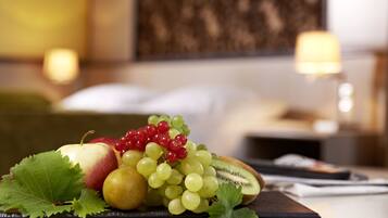 Een fruitschaal op een tafel, met een bed en nachtkastje op de achtergrond.
